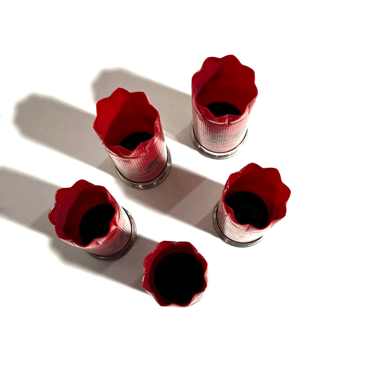 Five red Winchester 12 gauge empty shotgun shells viewed open-end up showing crimped mouths on a white background