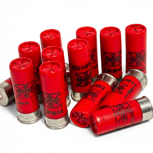 A group of red shotgun shells arranged on a white background, with several standing upright and two lying on their sides. The shells are printed with black text and logos, including the brand name 'SUPER'.