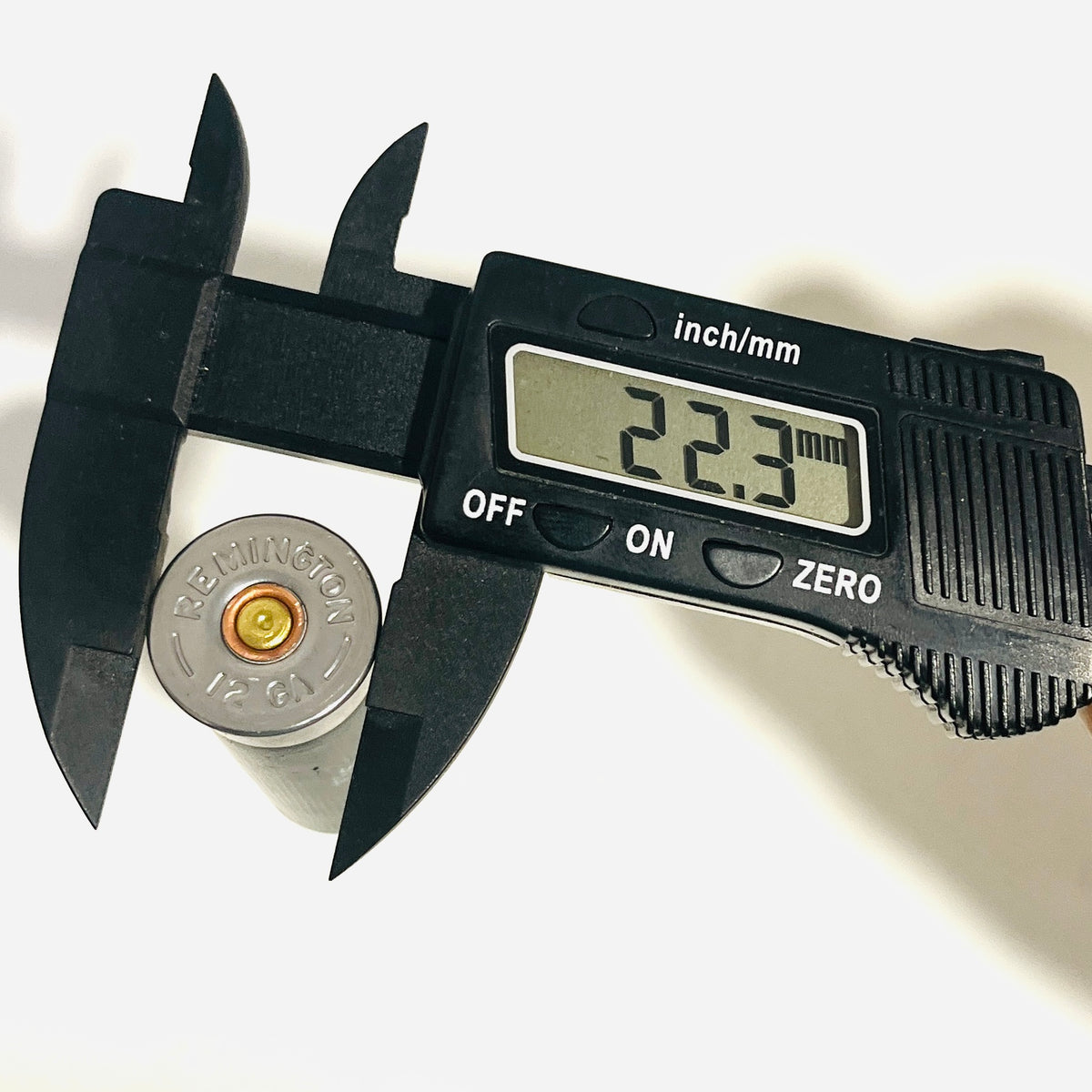 Digital caliper reading 22.3 mm across the headstamp rim diameter of a spent black Remington 12 GA shotshell
