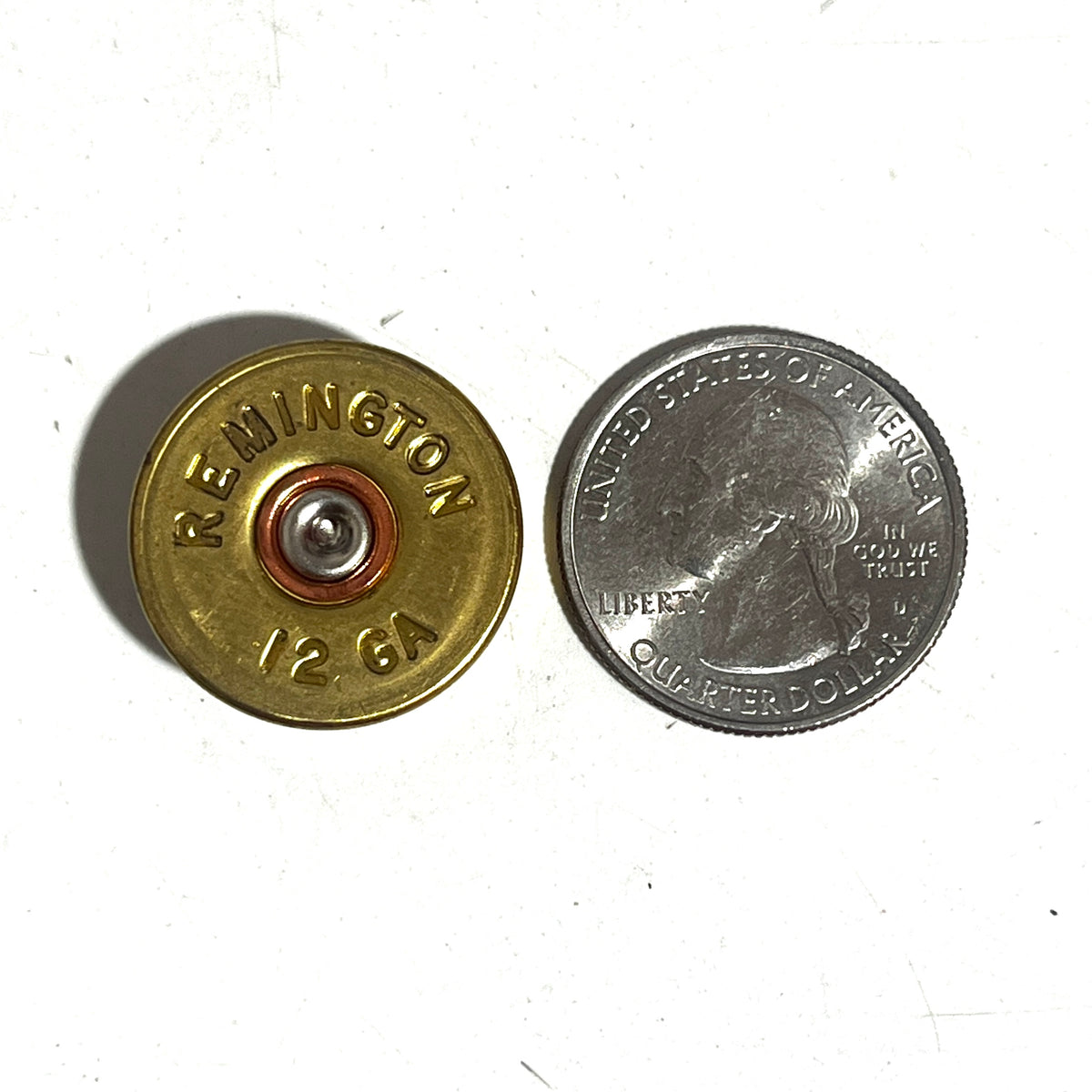 Remington 12ga headstamp gold color next to a US quarter for size reference, white background