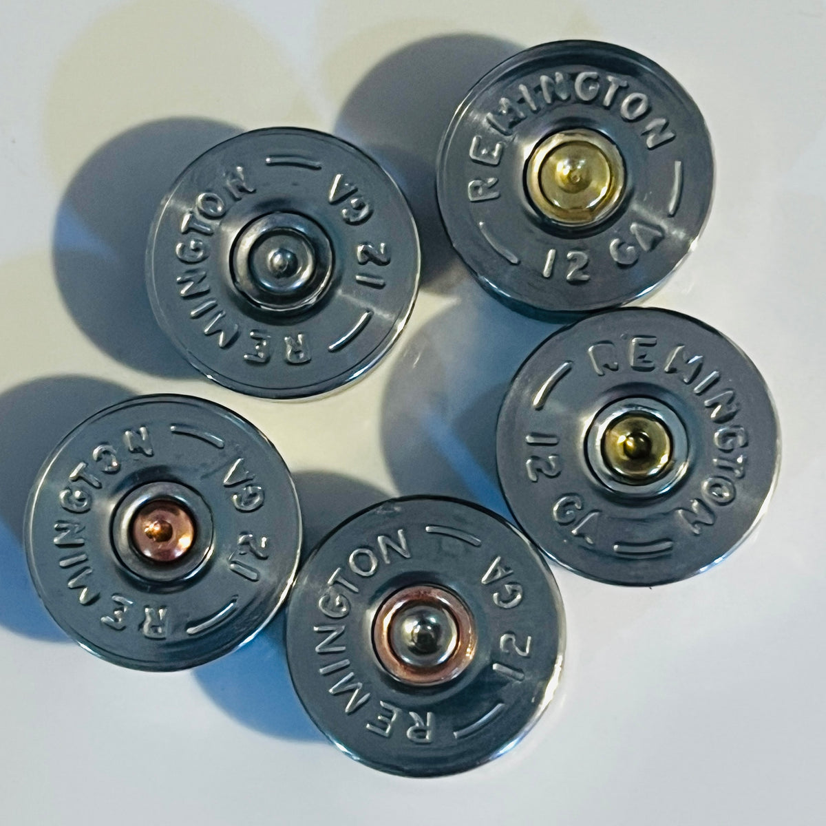 5 Remington 12 gauge cut bottoms mixed colored spent primers on white background