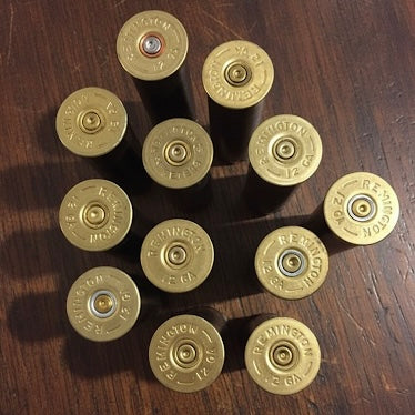 Close-up view of multiple gold shotgun casing headstamps arranged on a dark wooden background.