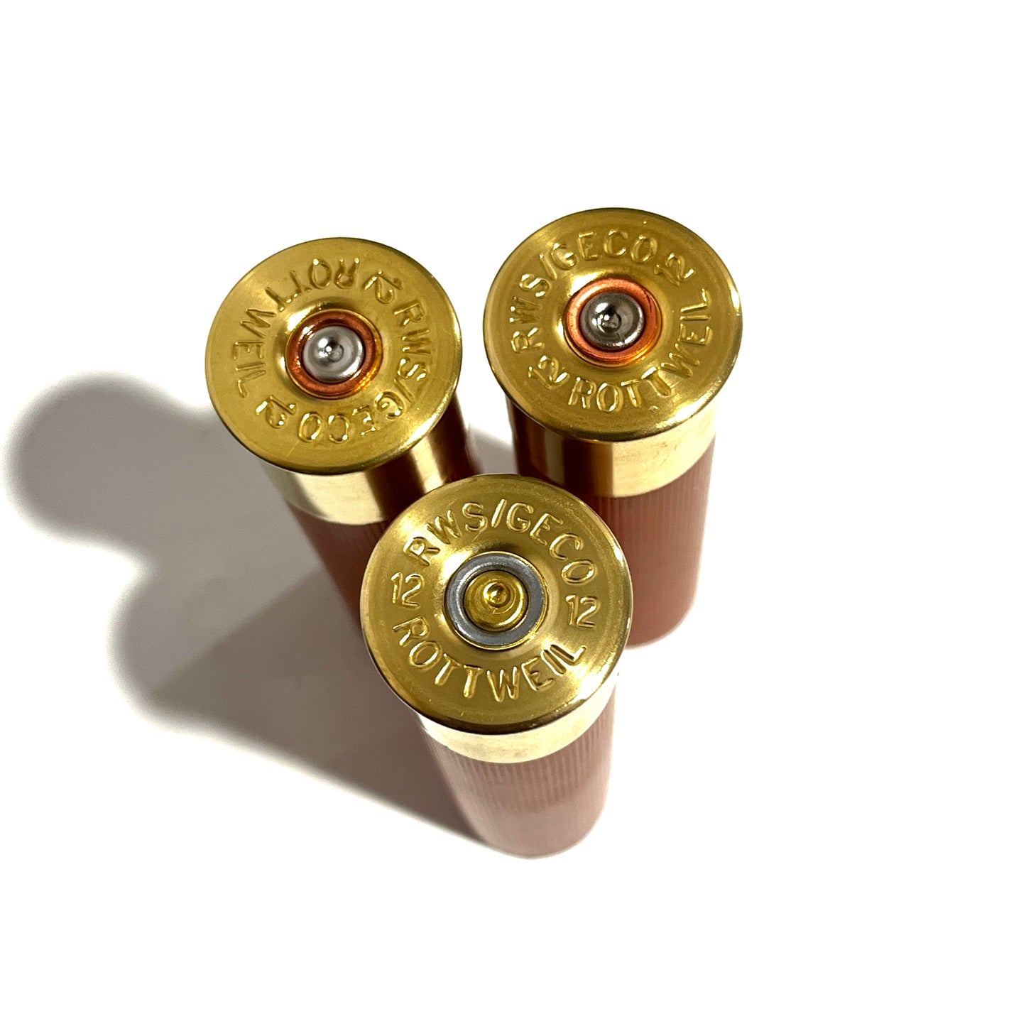 Three standing rose gold shotgun shells showing gold high brass headstamps, spent primers, and unmarked hulls.
