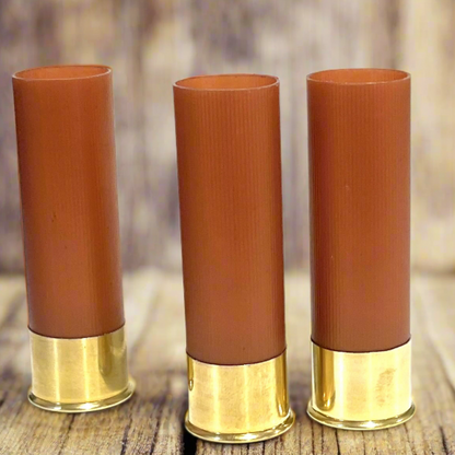 Three Empty Shotgun Shells rose gold 12 gauge hulls on rustic wood for DIY wedding boutonnieres and decor.
