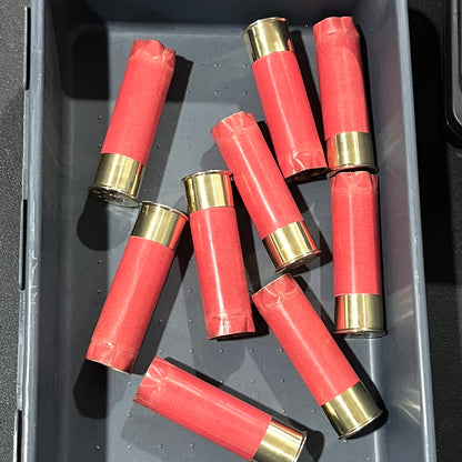 9 salmon pink paper shotgun shells lying in a plastic storage tray