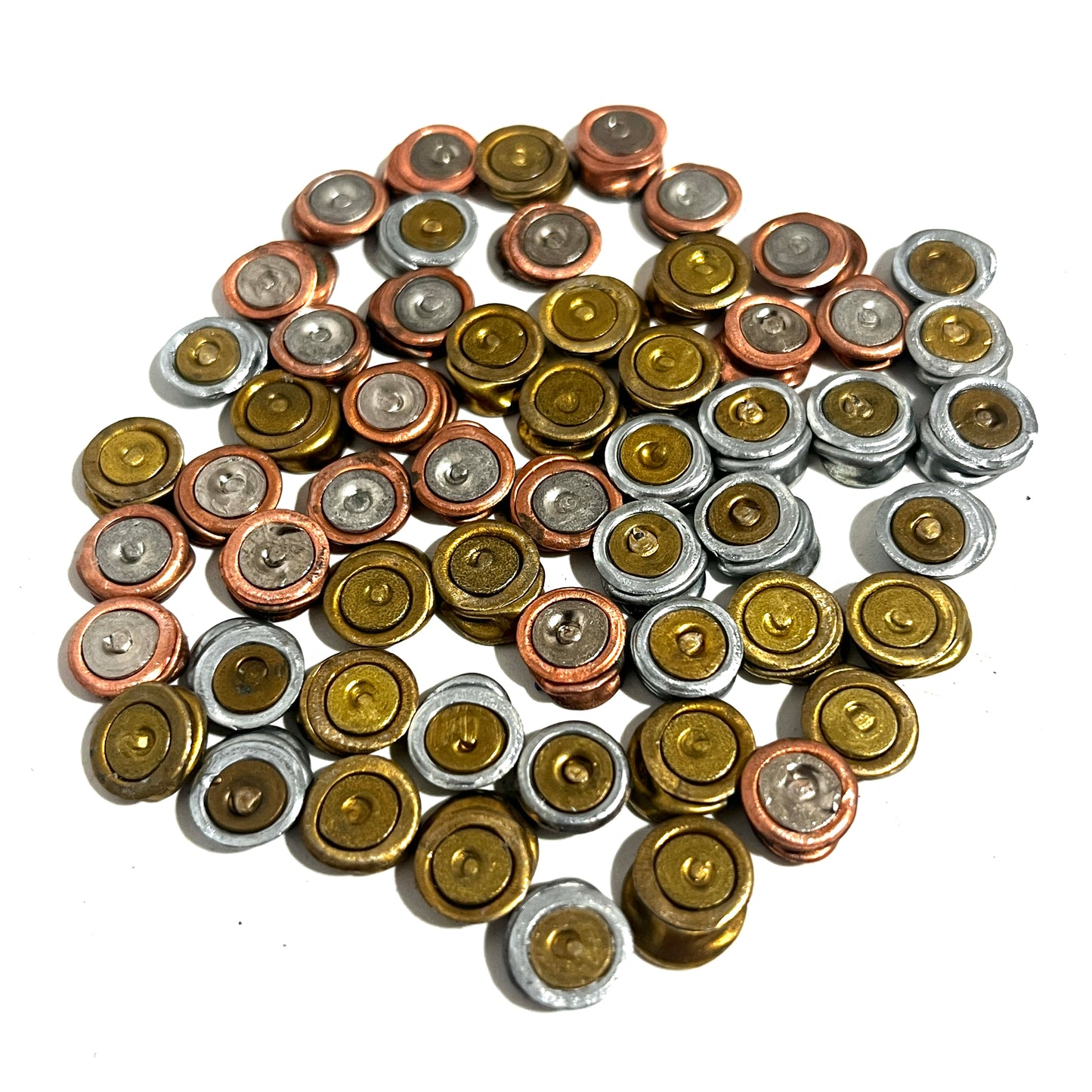 A collection of scattered spent primers arranged loosely in a ring formation against a bright white background for jewelry design.
