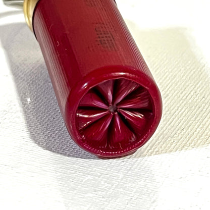 Close-up of red 12 gauge shotgun shell keychain crimp detail, ideal for EDC gear, hunting gifts, or a unique zipper pull.

