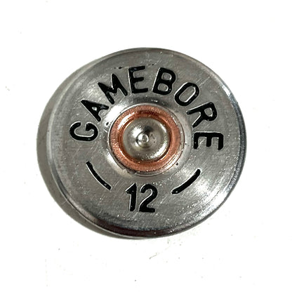 Close-up of a round silver Gamebore 12 gauge shotgun shell slice with a copper primer center