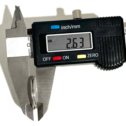 Digital caliper measuring the thickness of a silver shotgun shell slice showing 2.63 mm