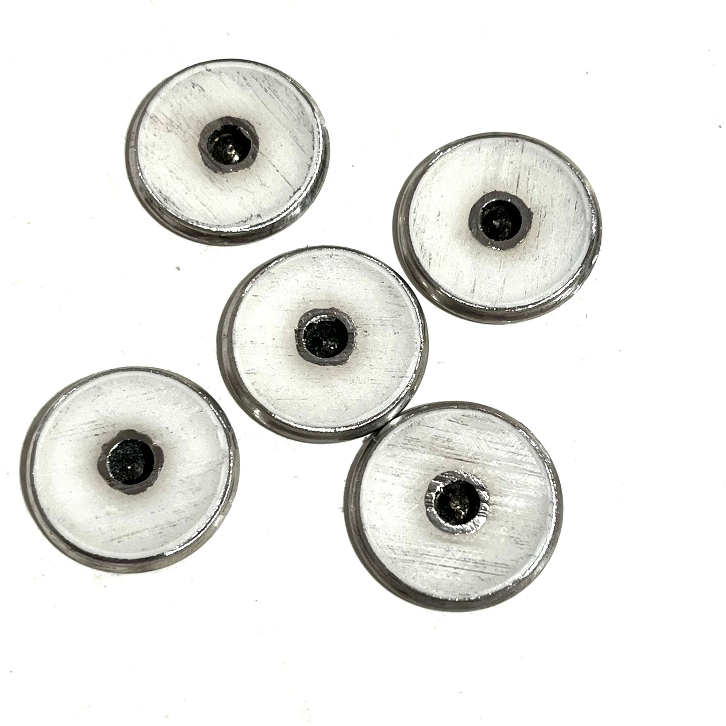 5 round shotgun shell slices viewed from the underside showing white enamel-lined centers