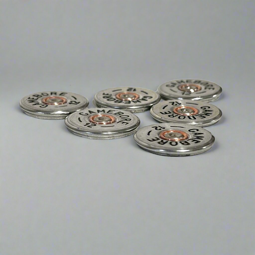 6 round silver Gamebore 12 gauge shotgun shell slices scattered on a gray background