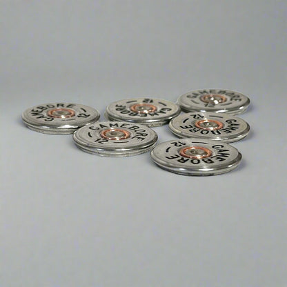 6 round silver Gamebore 12 gauge shotgun shell slices scattered on a gray background