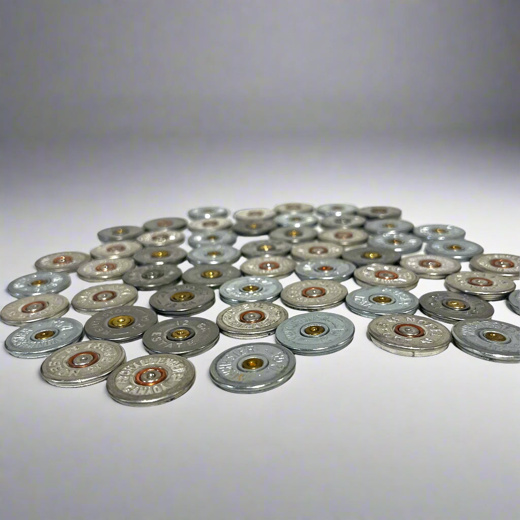 A pile of silver shotgun shell slices with various headstamps and gold or copper primers