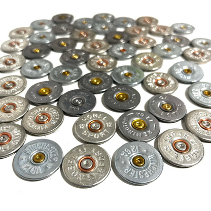 A pile of silver shotgun shell slices with various headstamps and gold or copper primers