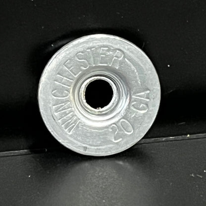 Silver Winchester 20 GA shotgun shell slice on a black background at an angle