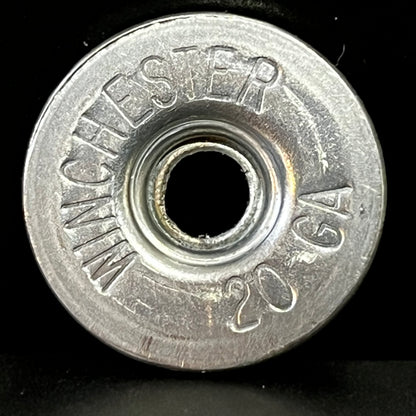 Close-up of a silver Winchester 20 GA shotgun shell slice on a black background