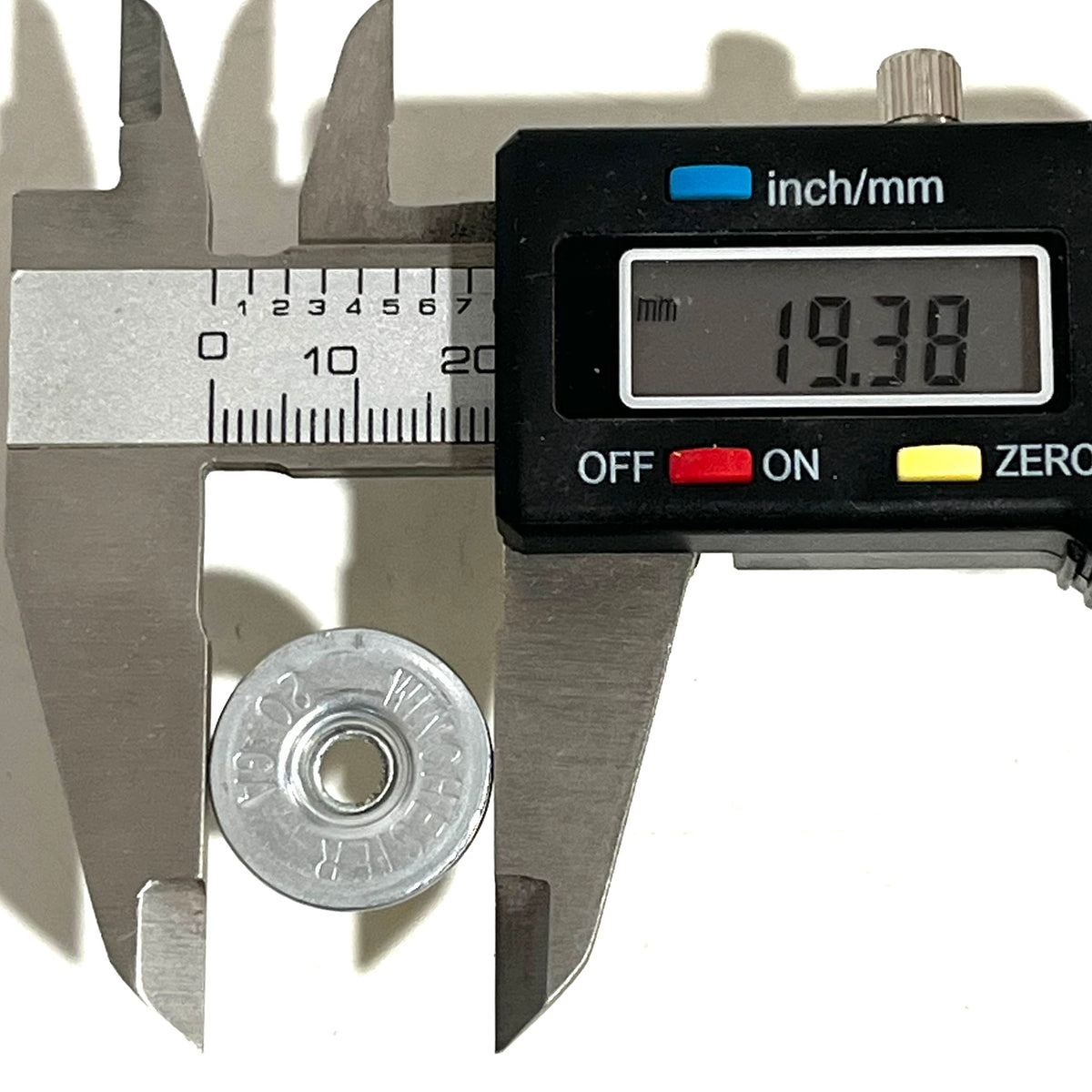 Digital caliper measuring the diameter of a silver Winchester 20 GA shotgun shell slice at 19.38 mm