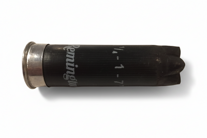 Single black spent Remington 12 gauge empty shotgun hull with silver base lying horizontally showing white printed lettering.