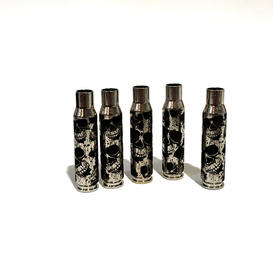 5 nickel .308 WIN cartridges engraved with a skull design, standing upright on a white background