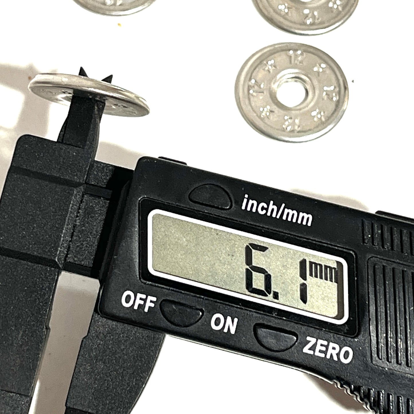 Digital caliper measuring the thickness of a flattened 12 gauge shotgun shell slice at 6.1mm, other slices in background