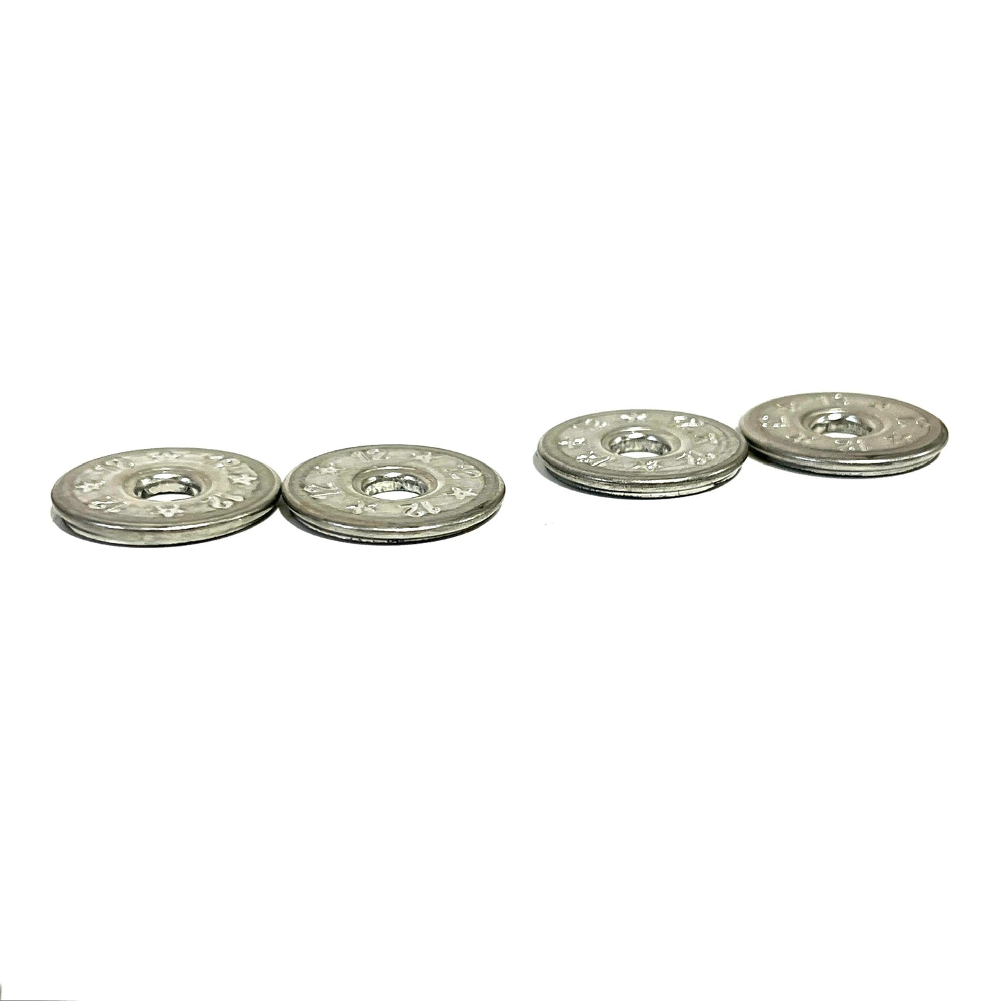 4 flattened silver 12 gauge shotgun shell slices in two pairs on white background, star and floral embossed pattern