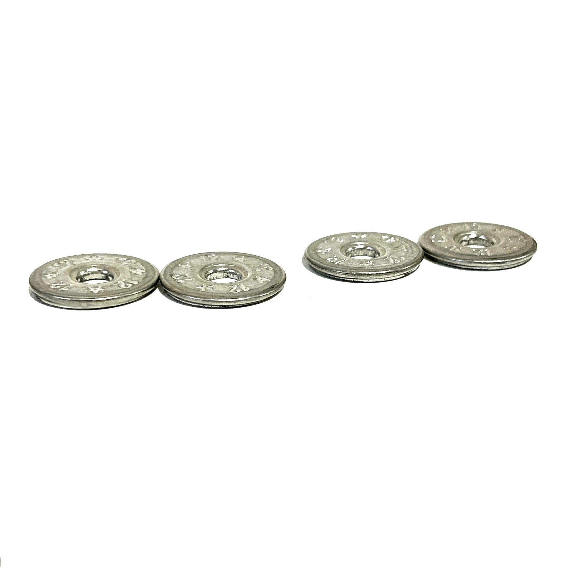 4 flattened silver 12 gauge shotgun shell slices in two pairs on white background, star and floral embossed pattern