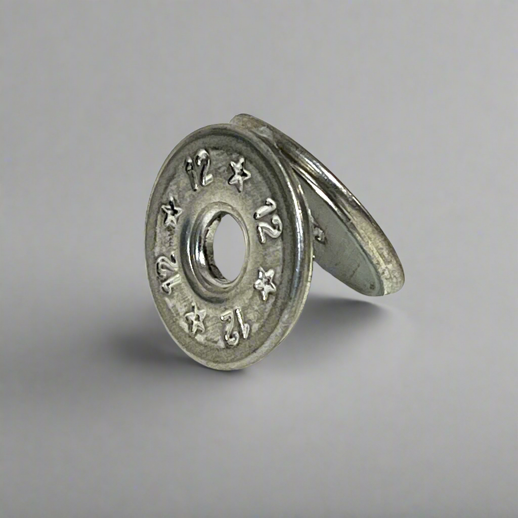 Two flattened silver 12 gauge shotgun shell slices leaning against each other, gray background