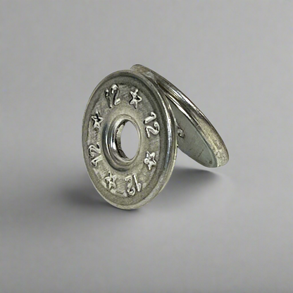 Two flattened silver 12 gauge shotgun shell slices leaning against each other, gray background