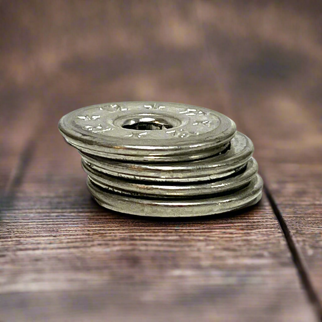 4 flattened silver 12 gauge shotgun shell slices stacked upright edge-on, deprimed center hole visible, dark wood background