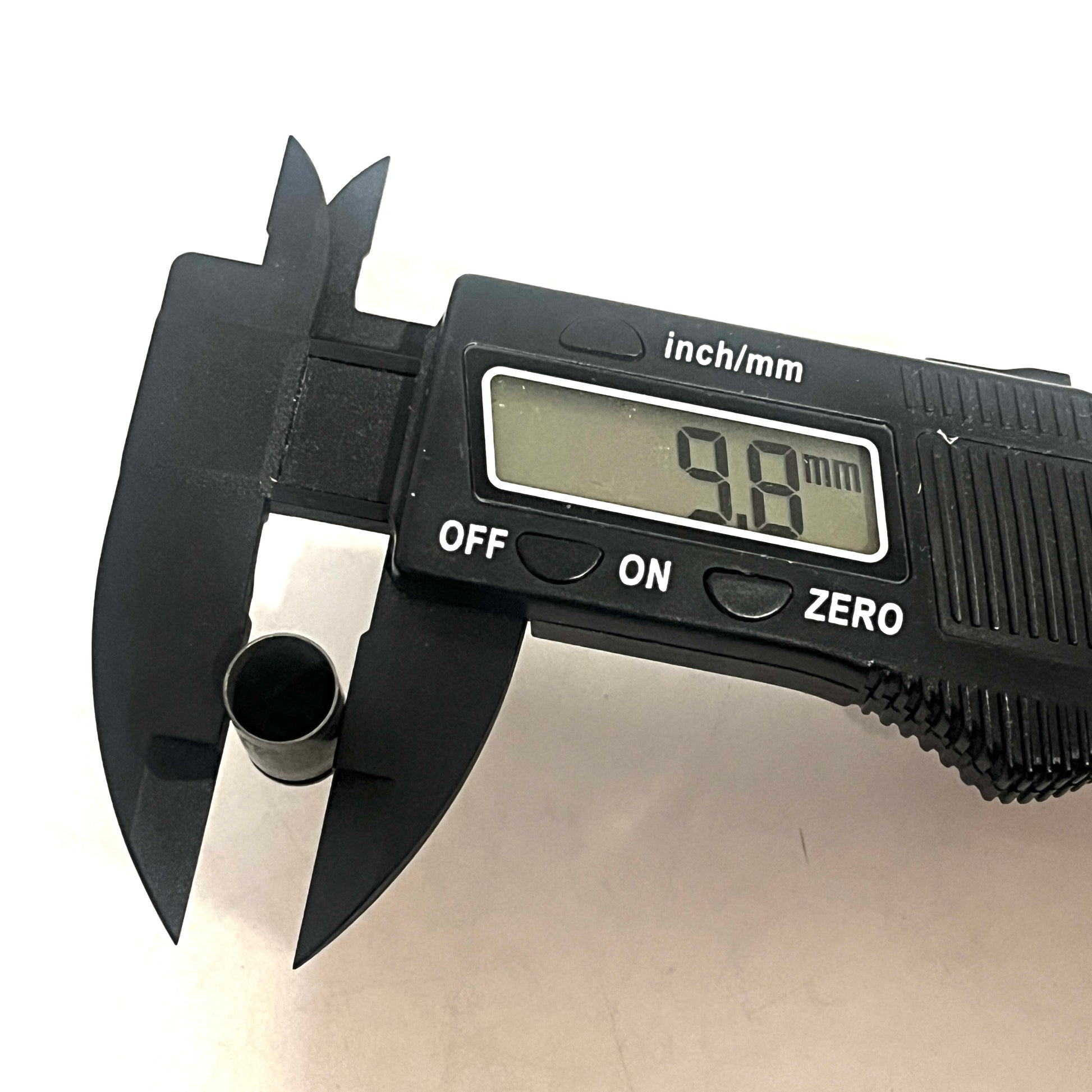 Digital caliper measuring the diameter of a steel 9mm casing at 9.8 millimeters