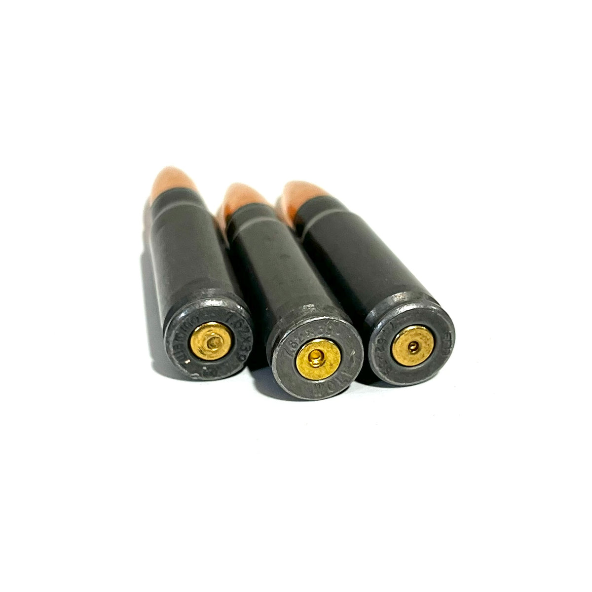 Three steel dummy rounds lying base-first, showing spent primers and dark steel casings.