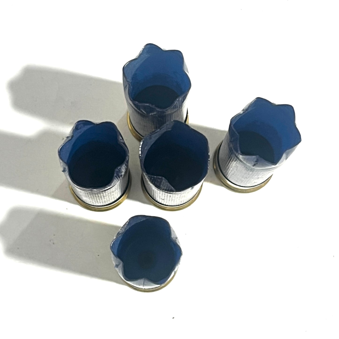 Five navy blue Sterling 12ga shotgun hulls viewed from above showing open star-crimped ends