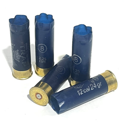 Five navy blue Sterling 12ga shotgun hulls with brass bases, one stamped TRAP, on white background