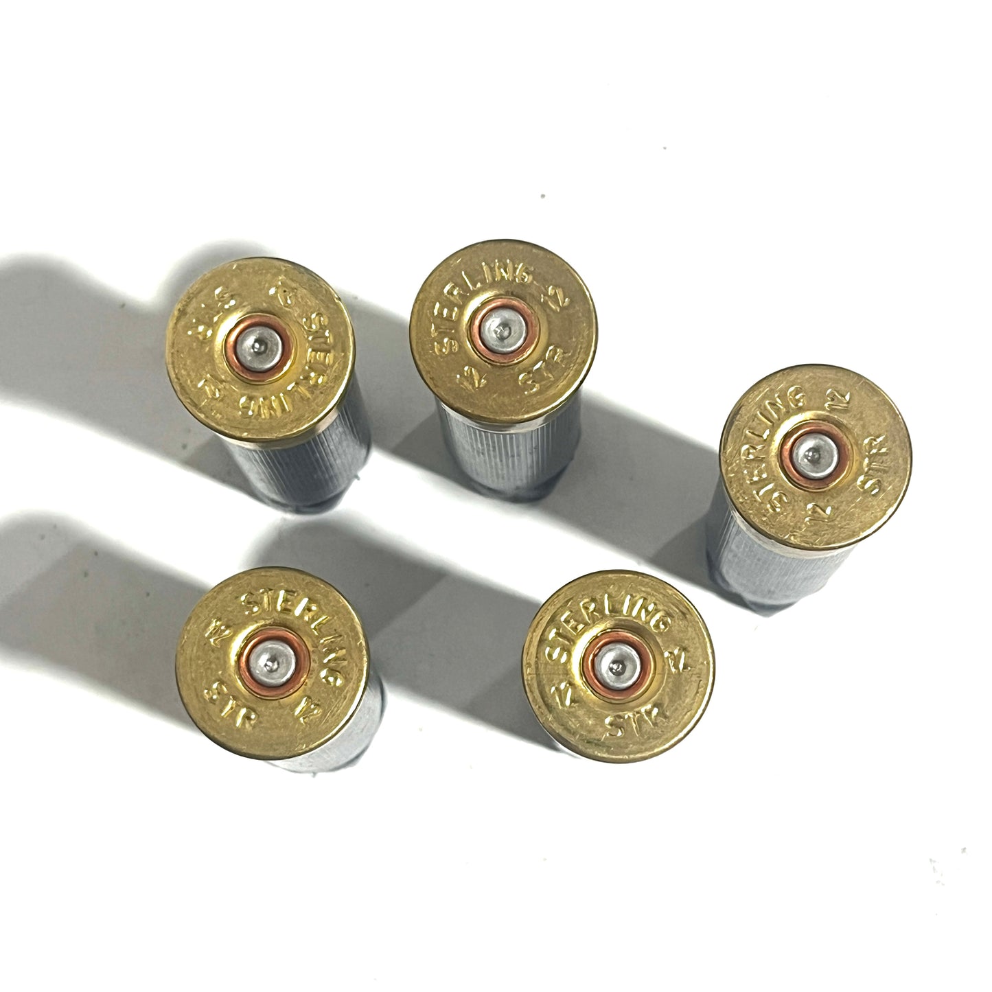 Five brass shell bases stamped STERLING 12GA, viewed from above with primers visible