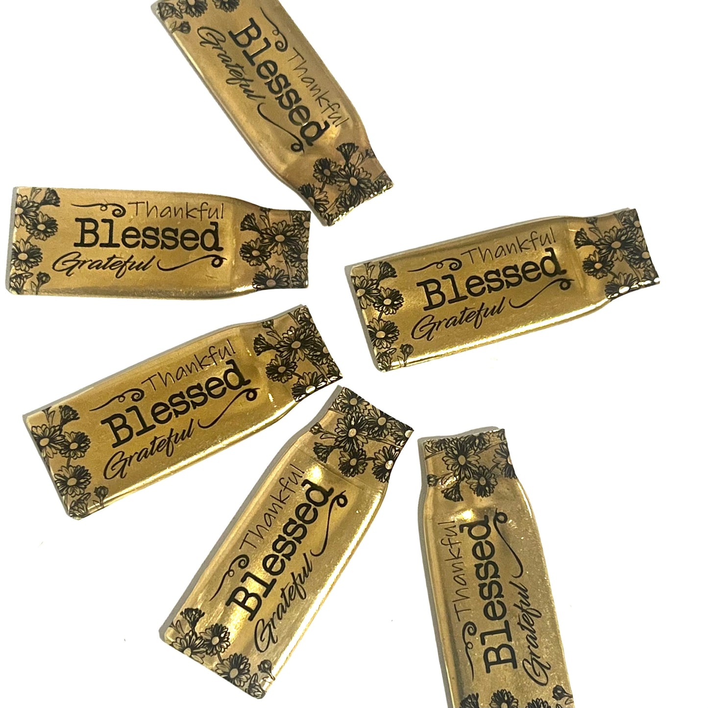Flattened .308 brass casings engraved with flowers and the words Thankful, Blessed and Grateful