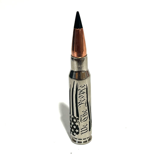 Nickel .308 rifle round with black polymer tip standing upright, engraved with We The People script and American flag stripes on white background