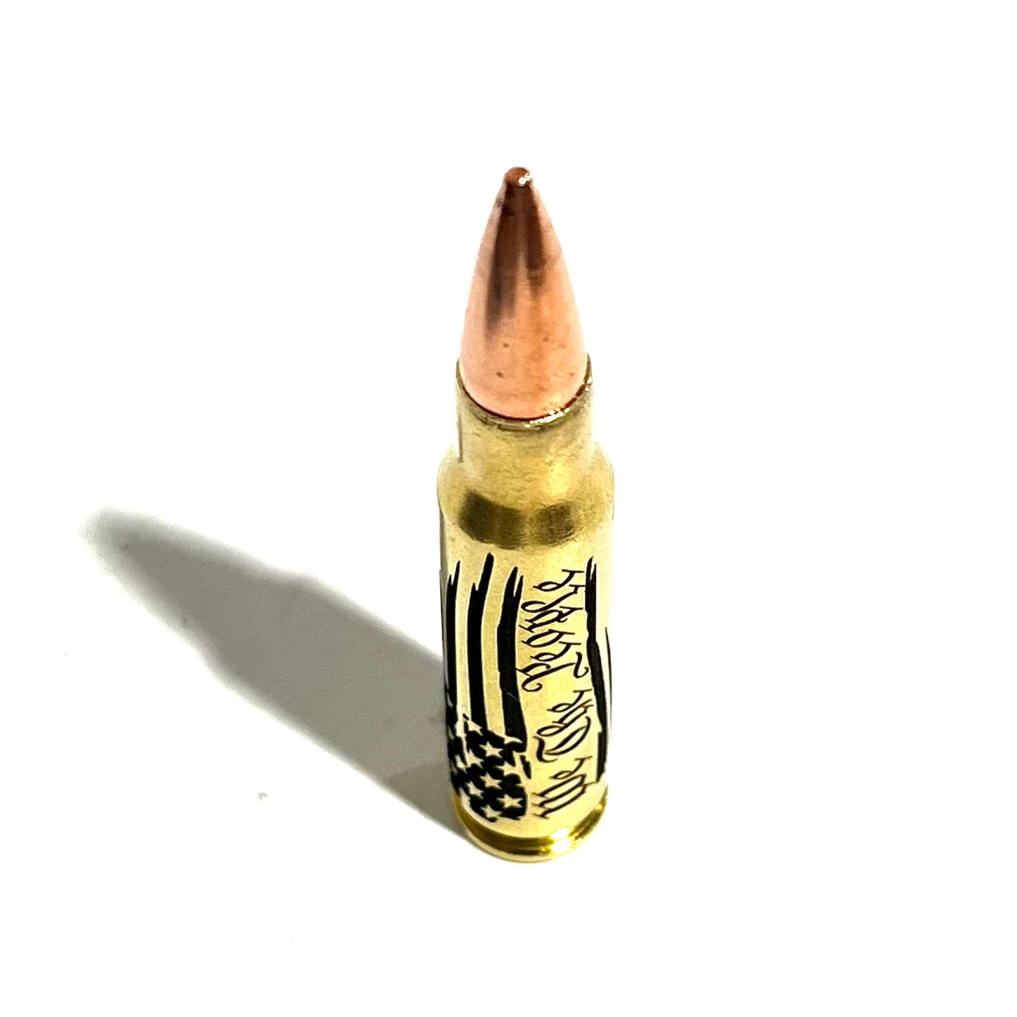 Brass .308 bullet with 'We The People' engraving, standing upright on white with dramatic shadow