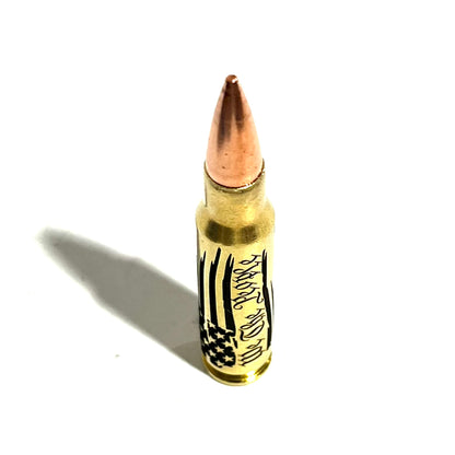 Brass .308 bullet with 'We The People' engraving, standing upright on white with dramatic shadow
