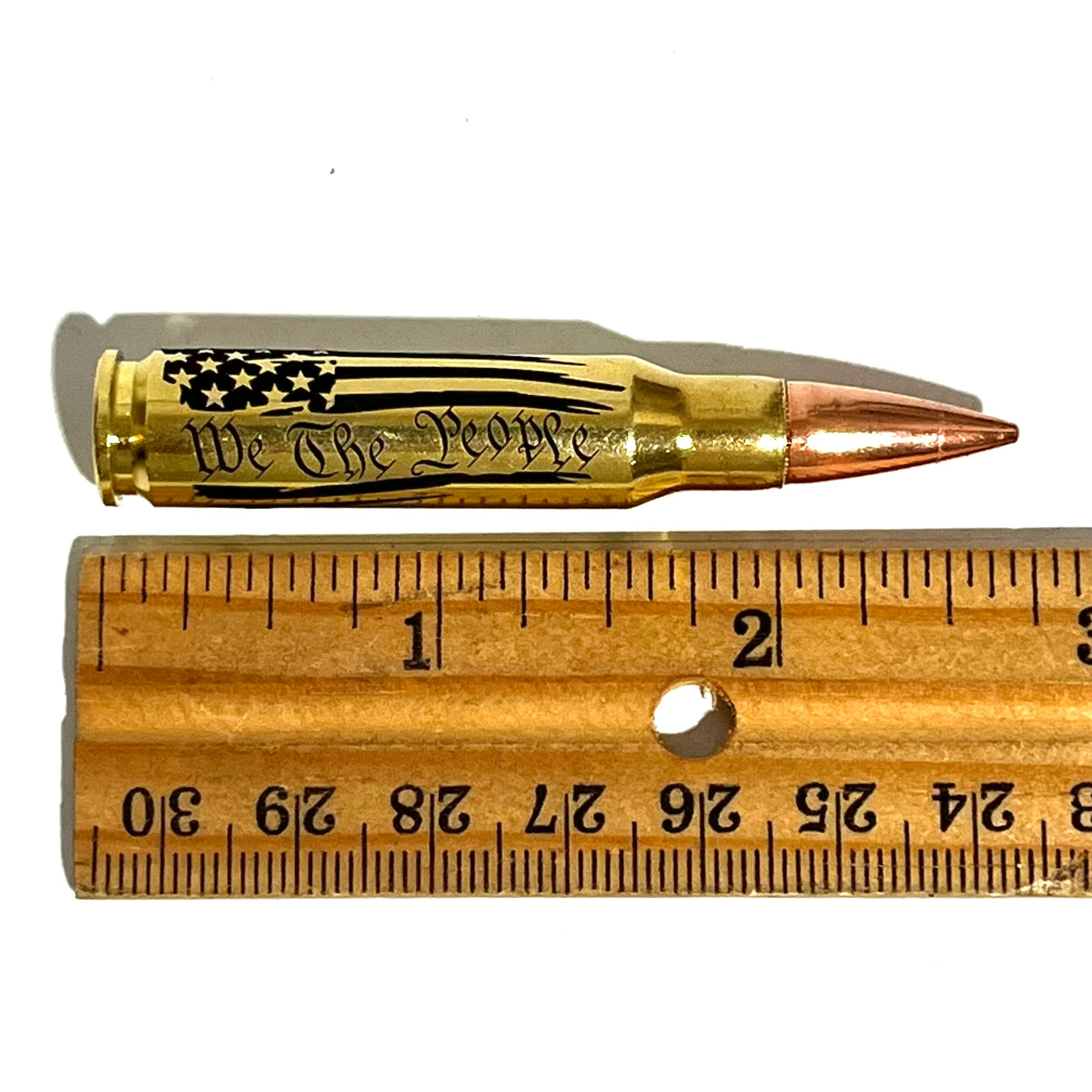 Brass .308 cartridge with 'We The People' engraving, shown above a ruler for scale
