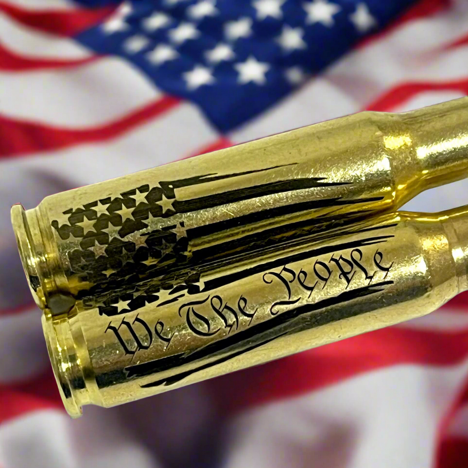 Extreme close-up of 'We The People' script and flag engraving on a brass .308 casing