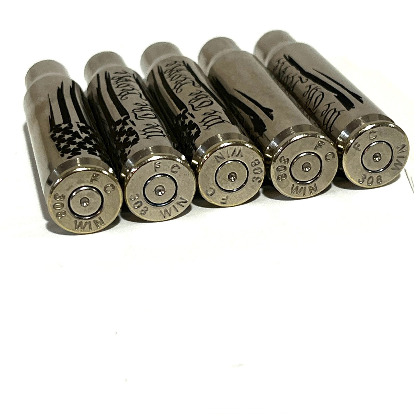 5 nickel .308 WIN cartridges engraved with We The People, lying on their sides showing headstamps reading 308 WIN