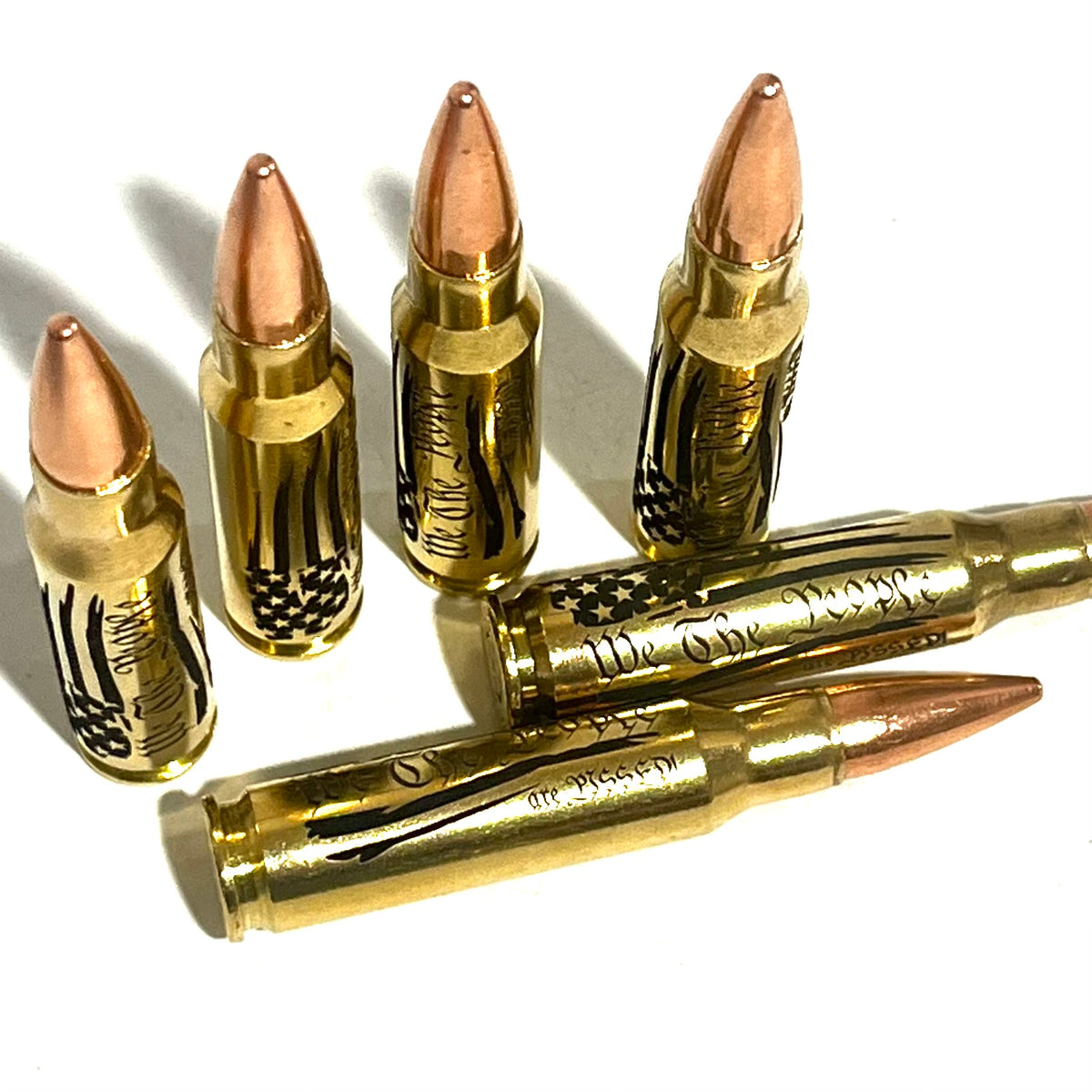 5 brass .308 WIN cartridges engraved with 'We The People' and a star-and-stripes design, white background