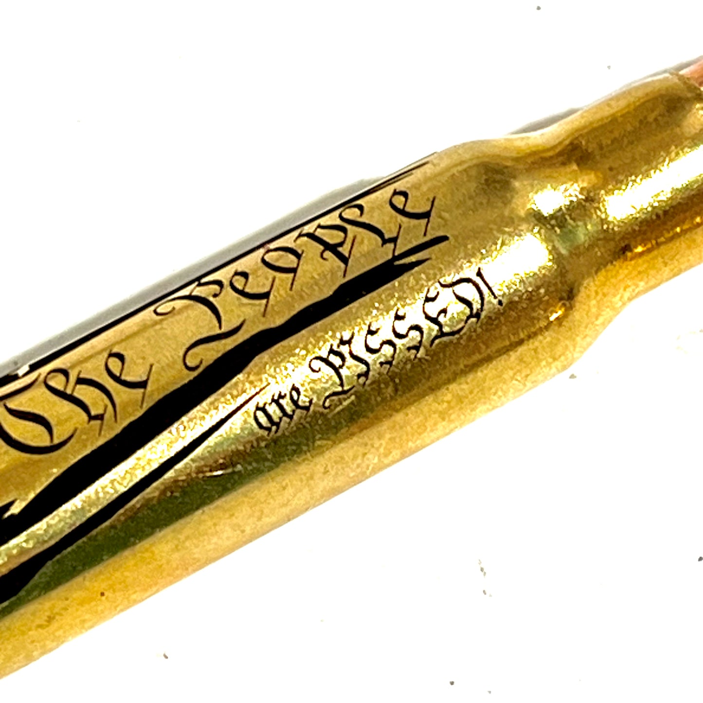 Extreme close-up of 'The People Are Pissed' engraving on a brass .308 WIN cartridge