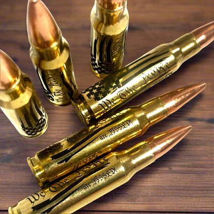 4 brass .308 WIN cartridges engraved with 'We The People Are Pissed' on a dark wood surface