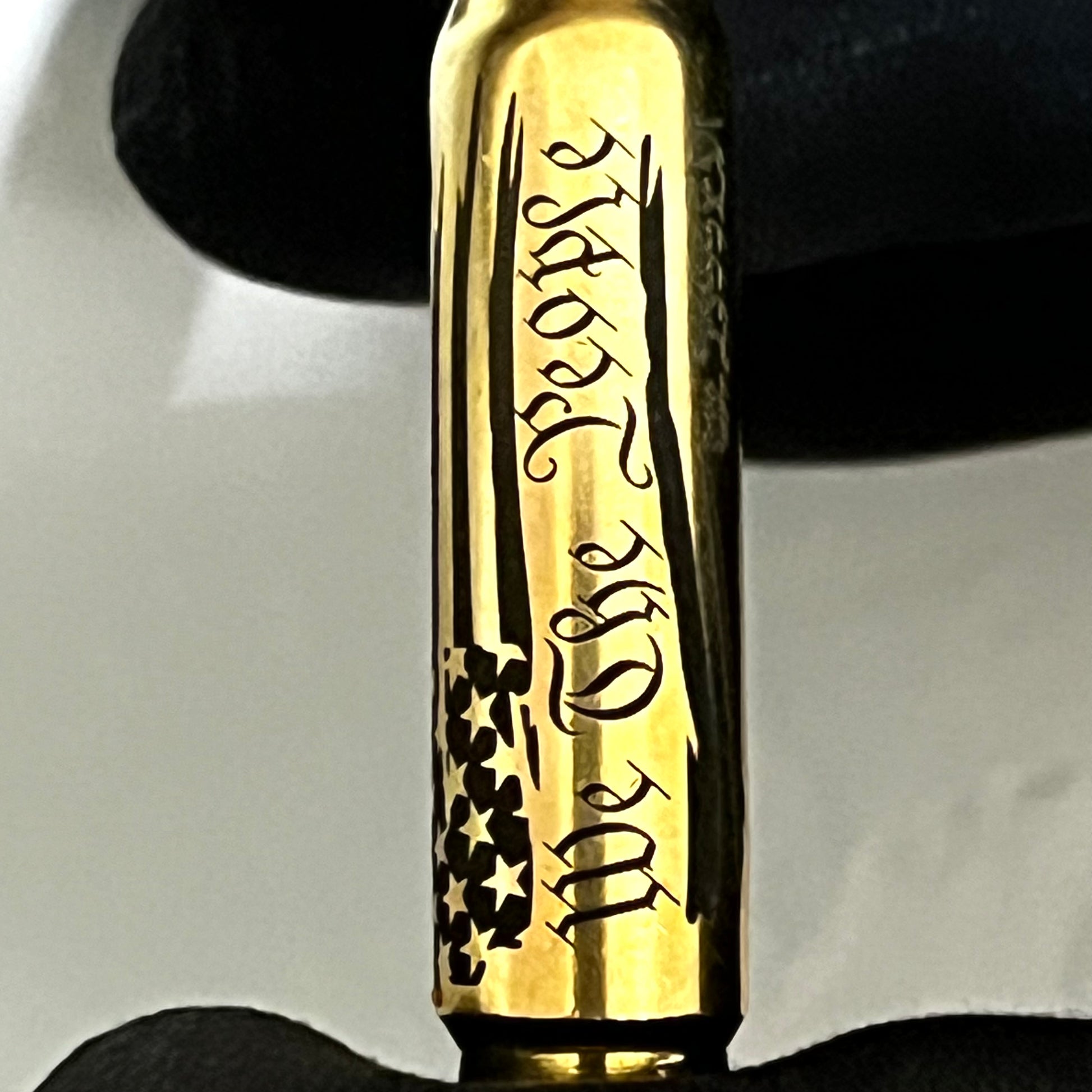 Extreme close-up of 'We The People Are Pissed' engraving on a brass .308 WIN cartridge