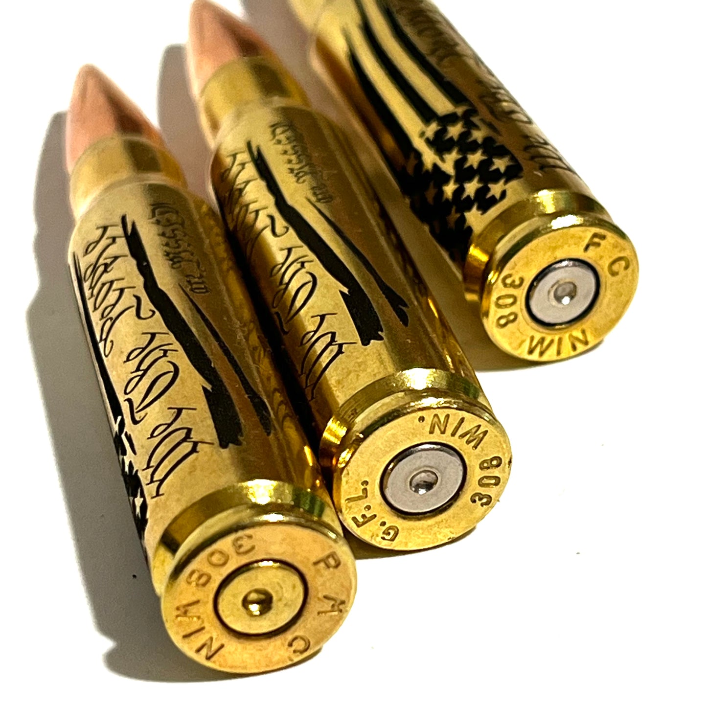 3 brass .308 WIN cartridges engraved with 'We The People Are Pissed' text, close-up