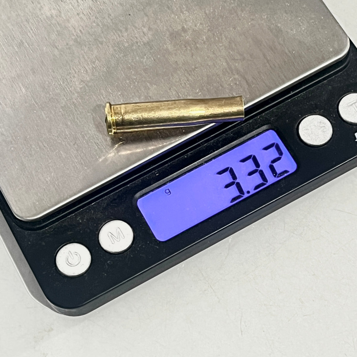 Brass .22 Hornet shell casing on a digital scale reading 3.32 grams