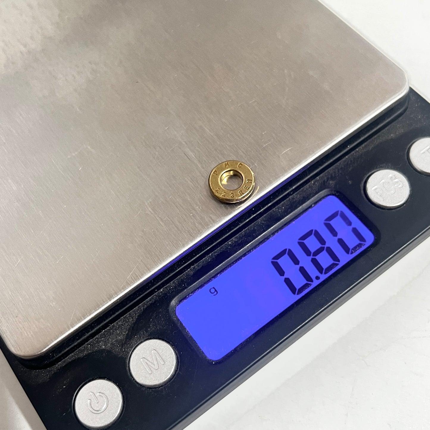 A deprimed brass bullet slice on a digital gram scale showing 0.80 grams