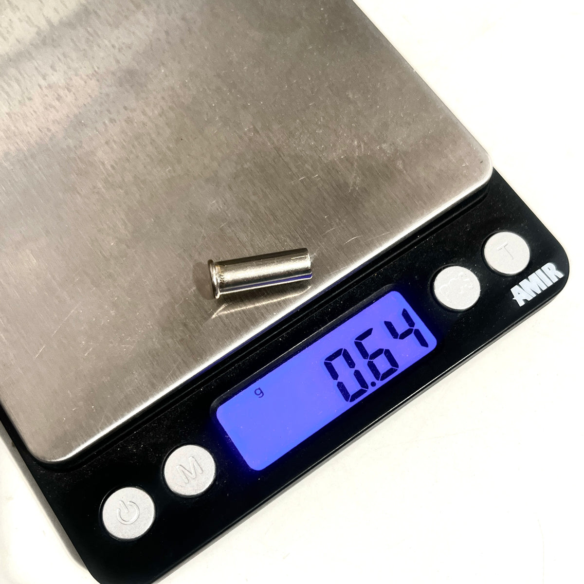 A nickel 22 caliber empty casing on a digital gram scale showing 0.64 grams