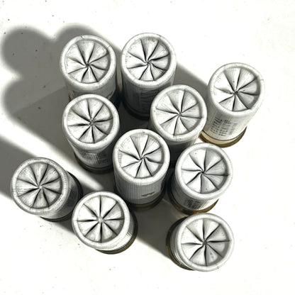 Ten white dummy shotgun shells viewed open-end up showing pinwheel folded crimps on a white background
